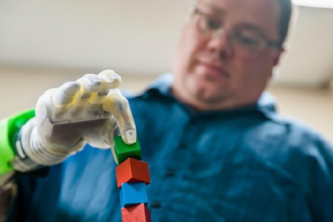 RPNI study participant Joe Hamilton controls a DEKA prosthetic hand to pick up blocks.