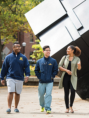 Three students walk in front of the Cube